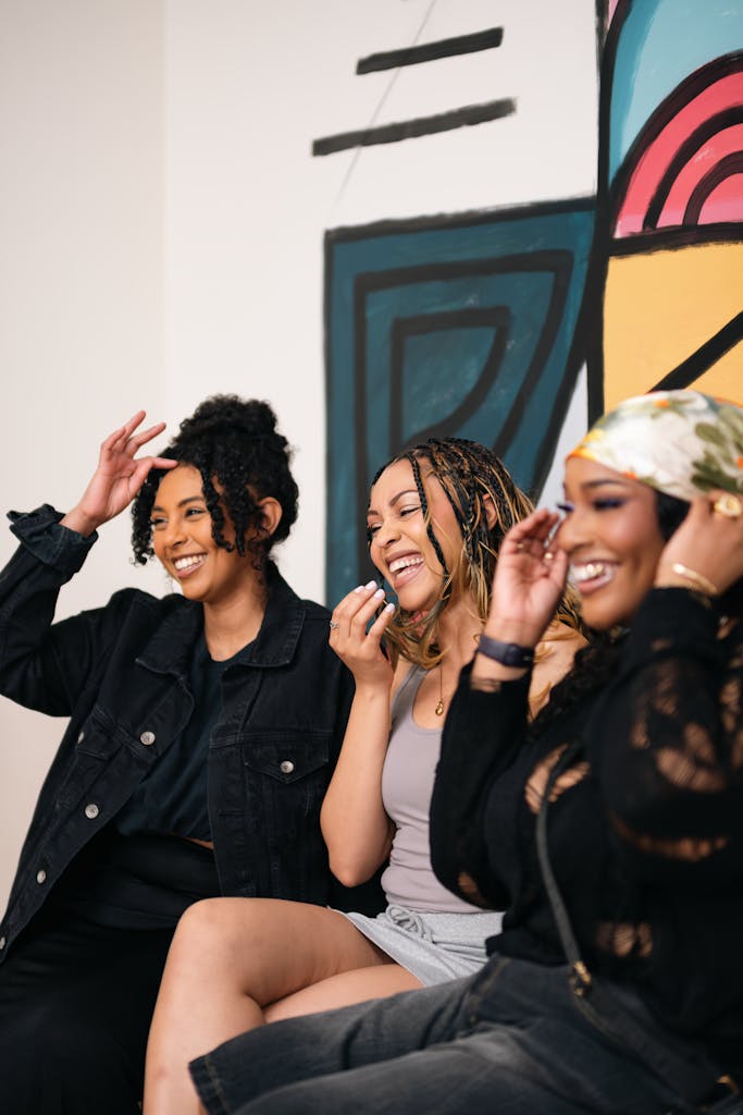 Three women enjoying a moment of laughter indoors at an art space in Dallas, Texas.